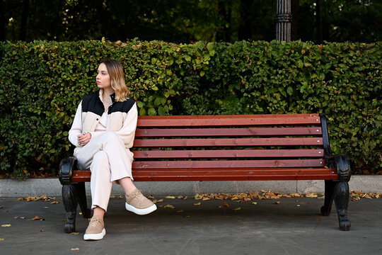 Young lonely woman sitting on a park bench and waiting for someone - Powered by Adobe