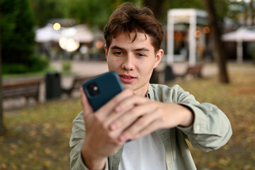 The guy is enthusiastically photographing something on his phone. Perhaps friend in the park or some incident to post on social networks