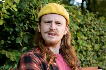 Young redhead guy expressing emotion of condemnation or disgust while looking at camera