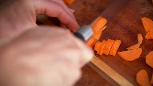 Cutting carrots with a chefs knife on a chopping board