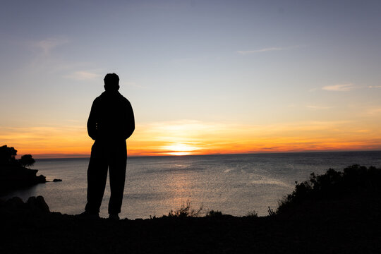 Person at sunrise at sea taking pictures