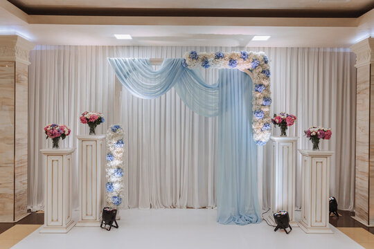 The photo zone at a wedding or birthday celebration is decorated with flowers and illuminated by artificial light