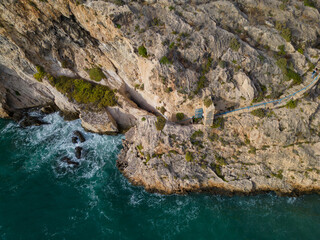 Naklejka na ściany i meble Aerial view of Xlendi cliff above footpath and steps towards Caroline Cave with few visitors at the end of the summer season on Gozo island.