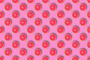 Creative seamless pattern of red coloured halves of oranges on pink background.