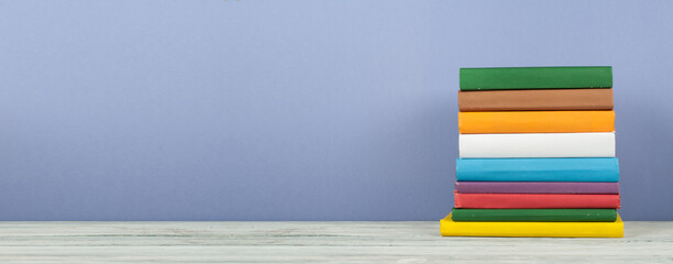 Book stack, hardback colorful books on wooden table and blue background. Back to school. Copy space...