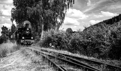 Historic steam train panorama in Plettenberg Sauerland Germany with idyllic rural landscape on narrow gauge Railway track. Tourist attraction with locomotive and vintage coaches, black and white