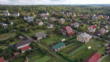 Picturesque eco-settlement, a village in the forest with fresh air. Cottage village among the forest, shooting from a height in the fall. Private houses, outbuildings, roads. Plots, private territory.