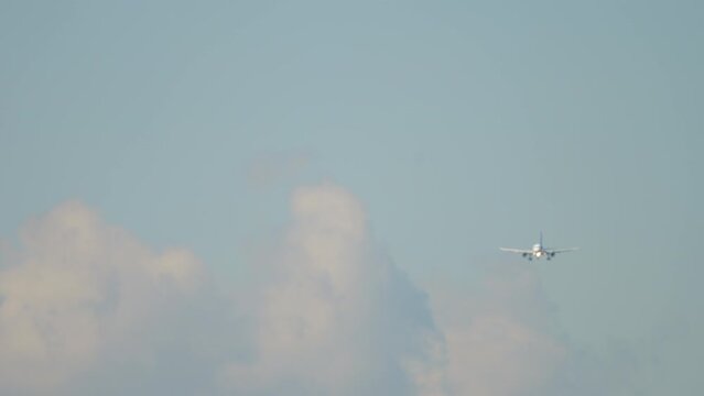Commercial jet airplane with an unrecognizable livery is approaching to land, long shot, front view
