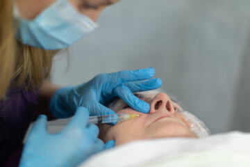 Naklejka premium A beautician wearing a surgical mask gives the patient an injection.