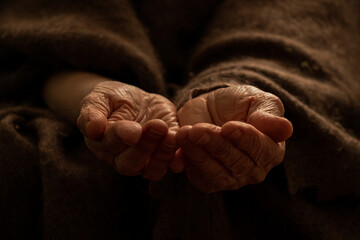 Outstretched hands of an old begging grandmother at home , need and helplessness, old hands of...