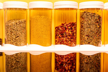 Spice rack with chilli flakes and curry seasoning on a yellow background