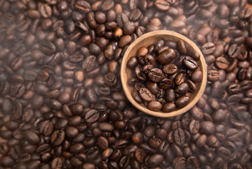 Top angle of roasted coffee beans in a small wooden bowl. Lightly smoked coffee beans. Concept for commercial product