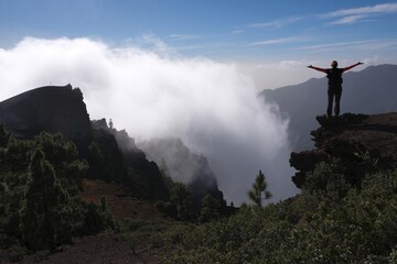 Silhouette of woman with raised arms in mountains over clouds. National Park Caldera de Taburiente, La Palma, Canary Islands, Spain