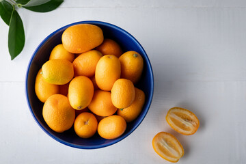Fresh kumquat in a blue bowl on a white background