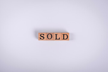 The inscription Sold made of wooden cubes on a plain background