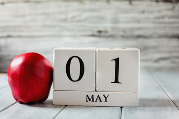 White wood calendar blocks with the date May 1st and a red apple for National Teacher Appreciation Day. 
