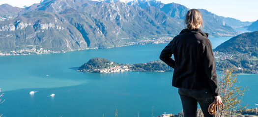 A hiker enjoying the magnificent view of Bellagio at lake Como seen from Monte Crocione - obrazy, fototapety, plakaty