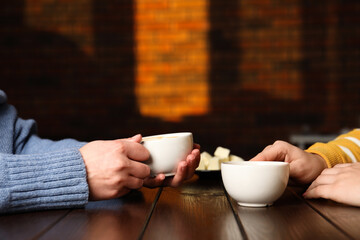 Women having coffee break at wooden table in cafe, closeup