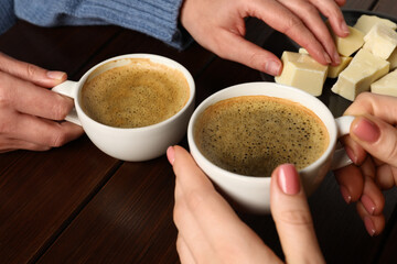 Women having coffee break at wooden table, closeup