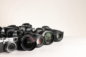 Modern cameras on white wooden table, space for text