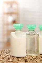 Mini bottles of cosmetic products on wicker mat against blurred background, closeup