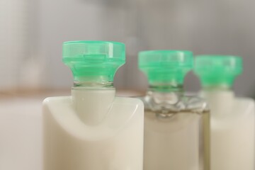 Mini bottles of cosmetic products on blurred background, closeup