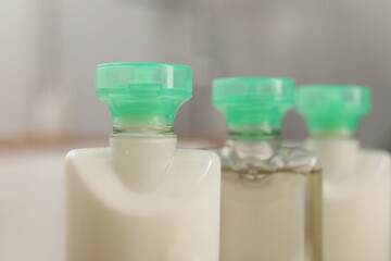Fototapeta na wymiar Mini bottles of cosmetic products on blurred background, closeup