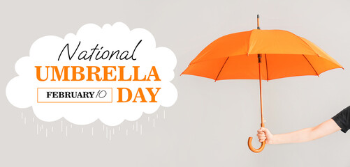 Female hand with umbrella on light background