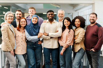 Group portrait of smiling multiracial business people looking at camera. Confident workers, colleagues  standing in modern office. Meeting. Successful business, career, startup team  - obrazy, fototapety, plakaty