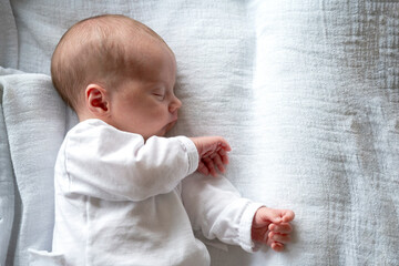 Close Up Photography of Peaceful newborn baby sleeping on its left side, radiating innocence and calm. Sleeping peacefully on its side, wearing white pajama on white bed. White background. 