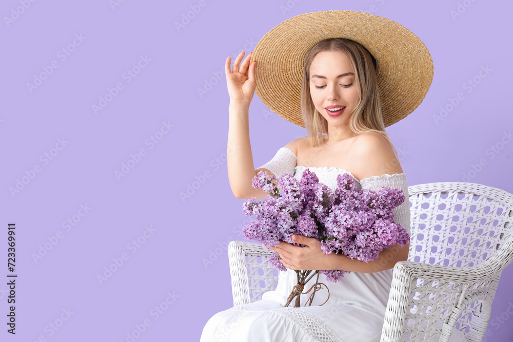 Poster Young woman with lilac flowers in armchair on color background