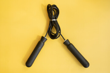 Skipping rope with black handles on the yellow background. 