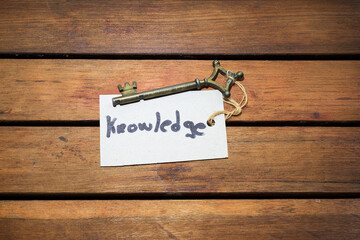 old key with the word knowledge written on a tag on a wooden background