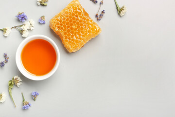 Obraz na płótnie Canvas Bowl with tasty honey, honeycomb and beautiful flowers on white background