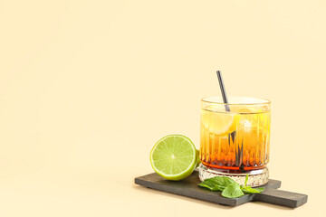 Cutting board with glass of delicious Long Island iced tea, lime and mint leaves on color background
