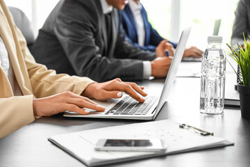 Businesswoman working with laptop at table in conference hall, closeup
