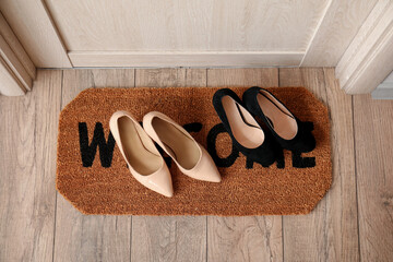 Doormat with female shoes in hall, top view