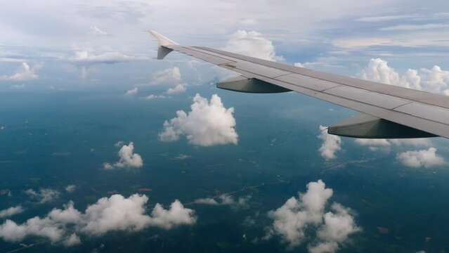 Classic footage through aircraft window onto wing. Flight view over clouds