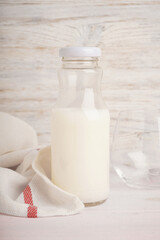 Obraz na płótnie Canvas Milk in jar and glass on a light wooden background.