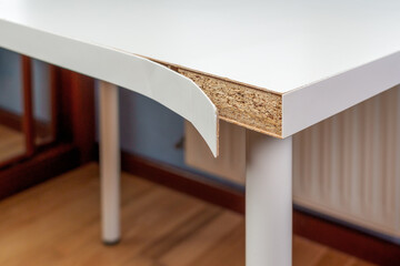 Damaged defective white table in a room with a peeling surface