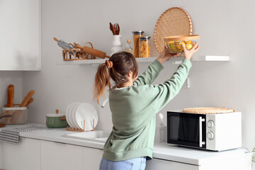 Pretty young woman with fruit basket in modern kitchen interior