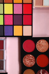Various colorful eyeshadow palettes on bright pink background. Flat lay.