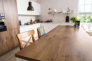 Island table with wooden chairs in interior of modern kitchen, closeup