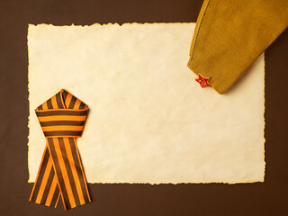 Victory Day 1945. The holiday is May 9. Military cap with star and St. George ribbon. A piece of old paper for your text