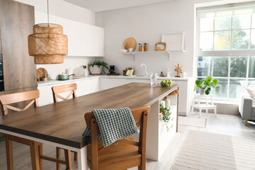 Clean island table with wooden chairs in interior of modern kitchen