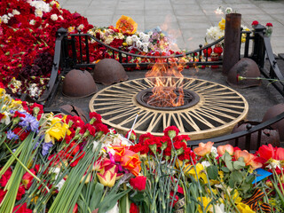 Eternal flame on a background of flowers on Victory Day on May 9, Victory Day at the memorial to...