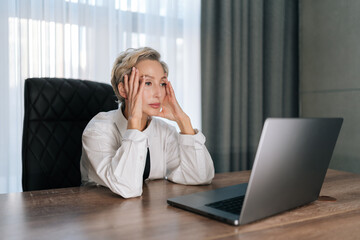 Stressed concerned middle-aged business woman working on laptop computer looking to screen, thinking solving problem at office. Serious female entrepreneur search for inspiration, feel lack of ideas.