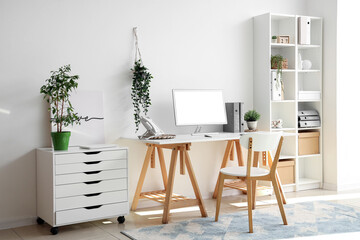 Interior of light office with workplace, shelf unit and drawers