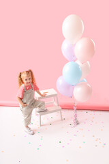 Cute little girl with beautiful balloons and step stool on pink background