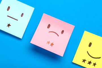 Sticky papers with rating smiles on blue background, closeup. Customer experience concept